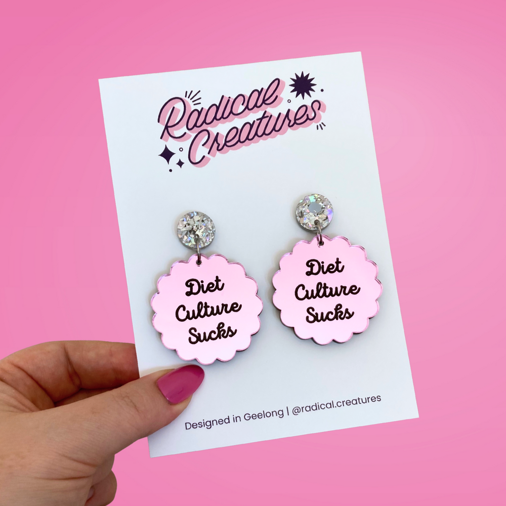 Scalloped circle shaped dangle earrings with sparkly earring topper. Pink mirror with text "diet culture sucks"