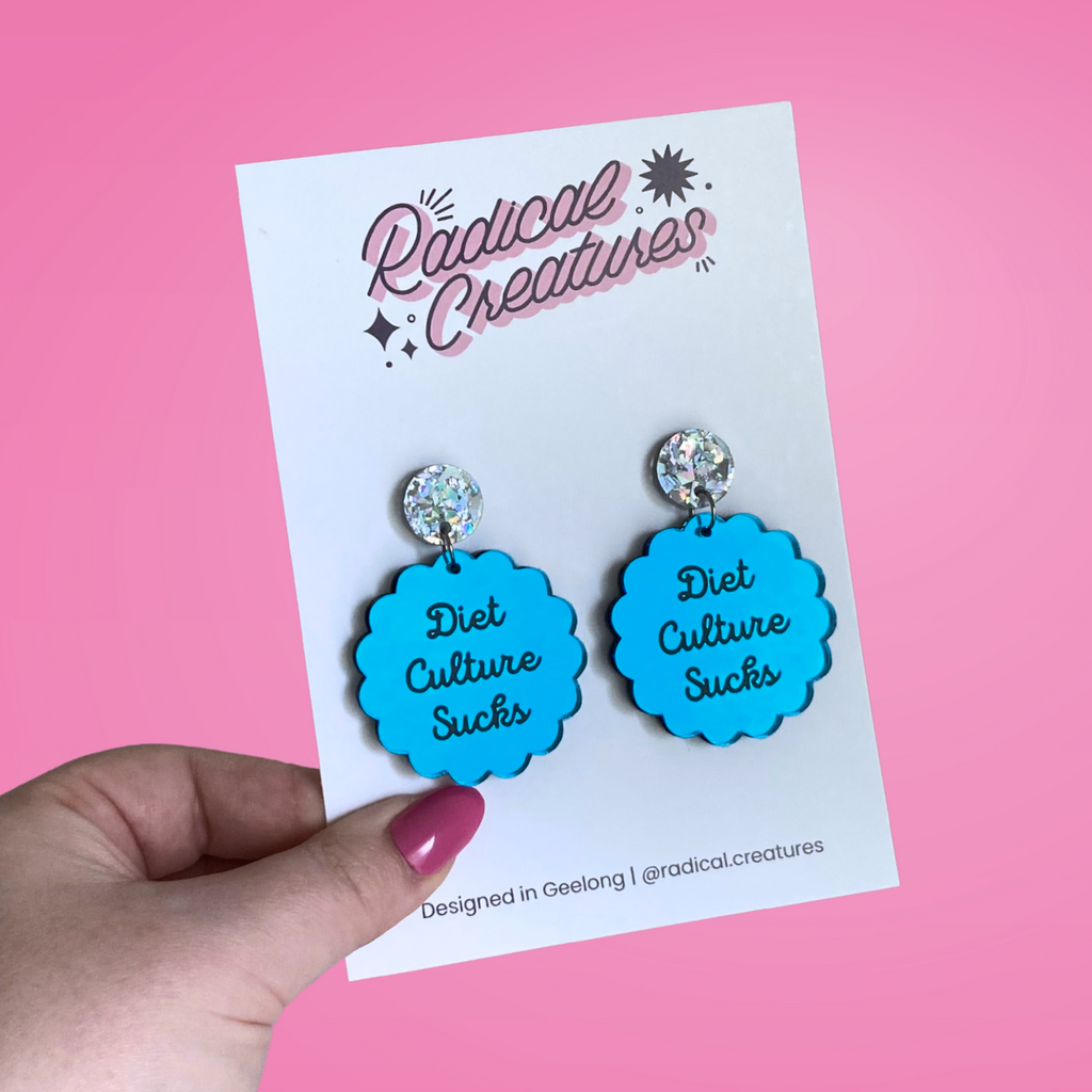 Scalloped circle shaped dangle earrings with sparkly earring topper. Blue mirror with text "diet culture sucks"