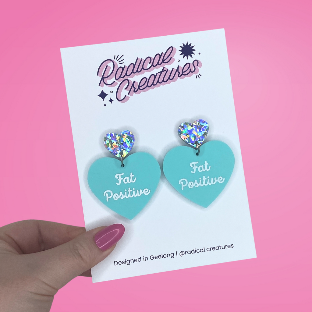 Pastel heart shaped earrings with sparkly heart shaped earring topper. Pastel mint green with words Fat Positive in white.