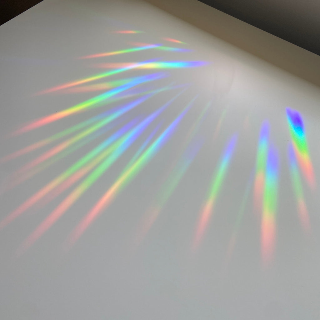 Image of rainbows light from the suncatcher sprayed across Laura's desk in the Radical Creatures studio